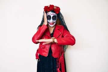 Woman wearing day of the dead costume over white looking at the watch time worried, afraid of getting late