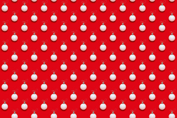 Creative pattern with white New years balls, holiday toys on bright red. Christmas greeting card. Minimal style background.