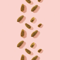 Christmas pattern from natural pine cone painted golden colored on pink. Trendy winter holiday background.