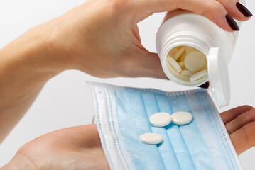 concept covid vaccine pills. COVID-19. Medical mask on a hand with white background. Medicine pills or Vaccine against the virus.