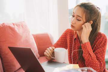 Work from home concept - Beautiful young woman in red pajamas shirt holding a cup of coffee. Working at home. Quarantine.