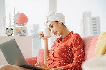 Work from home - Beautiful woman working instanly after taking shower infrontt of laptop computer, drinking coffe in the morning.