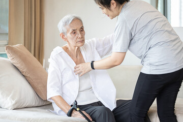 Asian daughter in charge is helping to dress up,chang clothes for a helpless old patient,taking...