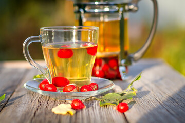A cup of hot rosehip tea on a wooden table in the autumn garden. Close-up.