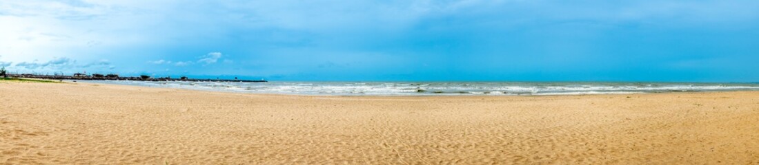 Seascape with sand beach under cloudy blue sky in Thailand