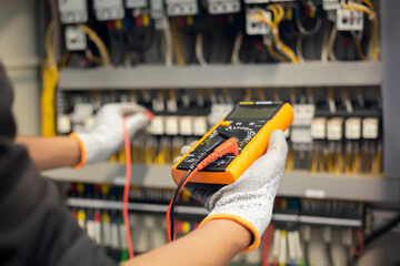Electrician engineer uses a multimeter to test the electrical installation and power line current...