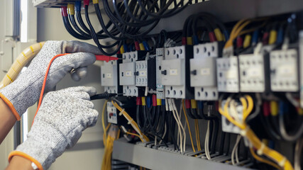 Electrician engineer uses a multimeter to test the electrical installation and power line current...