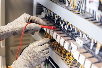 Electrician engineer uses a multimeter to test the electrical installation and power line current...