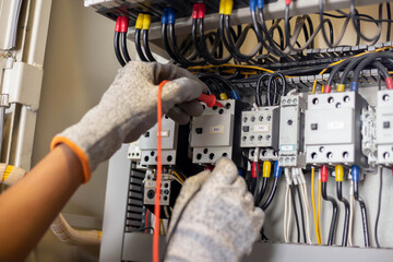 Electrician engineer uses a multimeter to test the electrical installation and power line current in an electrical system control cabinet. © A Stockphoto