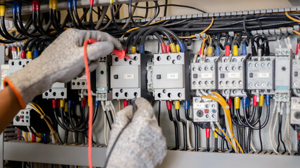 Electrician engineer uses a multimeter to test the electrical installation and power line current...