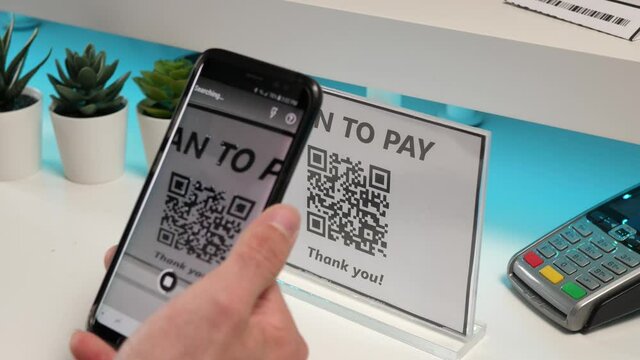Client of a store paying for his purchase using a QR code and his smartphone. Scanning the code with the mobile phone to make the payment.