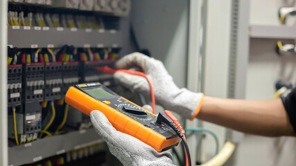 Electrician engineer uses a multimeter to test the electrical installation and power line current...