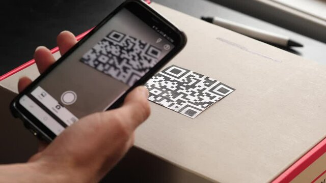 Scanning the QR code on a cardboard box with a mobile phone camera.