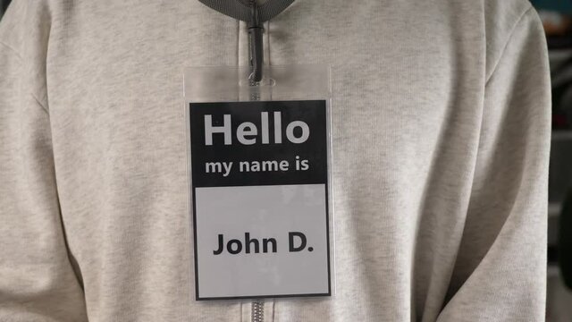 Man wearing a badge on his chest saying ''HELLO MY NAME IS JOHN D.'' to identify himself in front of the others.