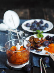 Process stage of making juice or smoothie from blue ripe plum. Mixer with plum and ingredients on a dark background.