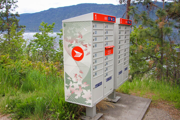 Canada post deposit location. The view on the mail box in the nature. Green grass, trees and lake in the background.