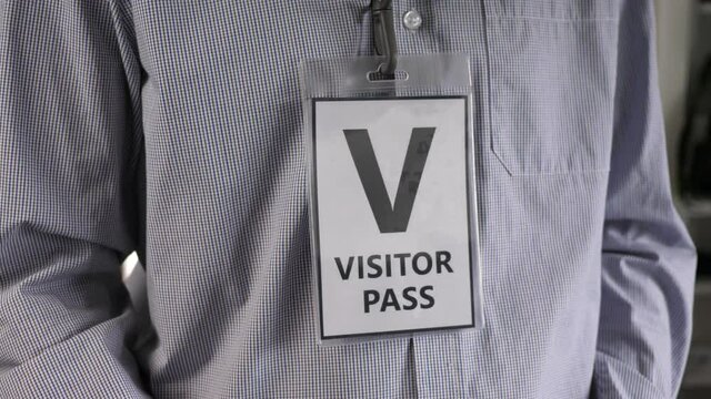 Wearing a visitor pass around his neck to identify himself.