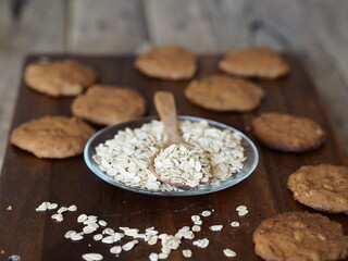 Homemade oatmeal cookies with whole grain rye flour in a glass plate with oatmeal grains on a kitchen board.Diet healthy food.