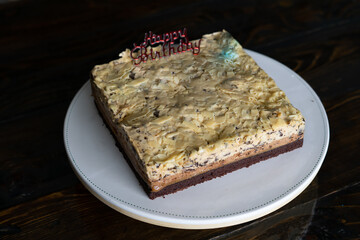 Three layer white  chocolate mousse cake with Happy Birthday topper on a cake base.