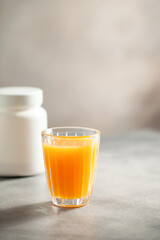 Powder collagen puts hand in glass of citrus juice.