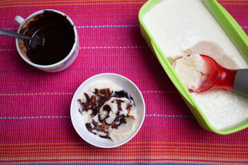 Vanilla ice cream with chocolate sauce and cookies Kerala, India. Top view of Home made chocolate brownies topped with in white plate on pink mat background.