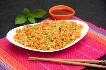 Schezwan Noodles or vegetable Hakka Noodles or chow mein, served in a bowl or plate with tomato...