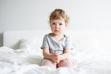 Fototapeta premium portrait of sad cute little girl sitting on bed