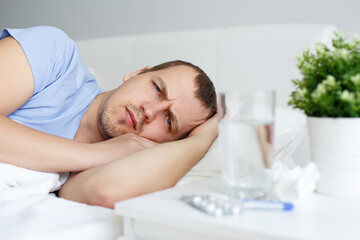Obraz na płótnie Canvas health care and illness concept - sick man lying on bed at home or hospital