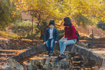 mother with little kid resting at autumn city public park