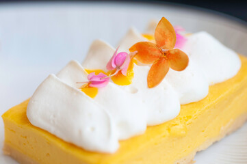 Obraz na płótnie Canvas Lemon chesse cake topping with white cream and beautiful flowers serve on white plate.