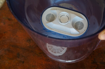 A male hand demonstrates a water jug with a new water purification cartridge installed.