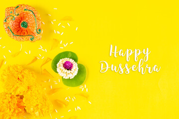 Happy Dussehra festival. Clay diya and flower on yellow paper background with text.