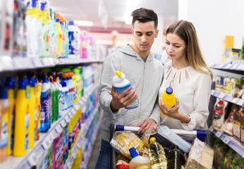 Young couple making purchases together, buying household chemicals in supermarket