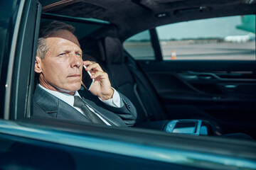 Businessman talking on cell phone in luxury automobile