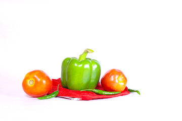 Green capsicum and tomato on the red colour pouch in a isolated white background