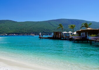 Best beaches of Aegean Sea - tranquil organized beach. Sporades islands of Turkey.Pure emerald water. Bamboo houses bungalows for rest on the water. Luxury travel conception