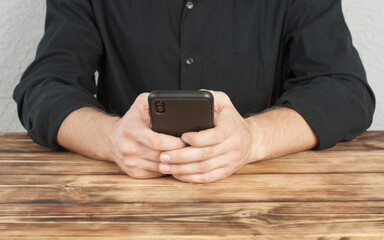 Young man with a phone in his hands. Sitting at the table. Businessman