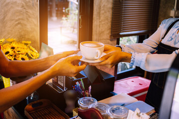 two Hand put a Latte arts coffee on wooden table.barista love art concept.