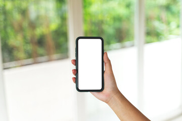 Hand holding empty screen smartphone at coffee cafe.