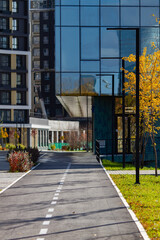Urban Landscape. Bike path leading to modern buildings, surrounded by green lawn on a beautiful sunny autumn day. Vertical shot