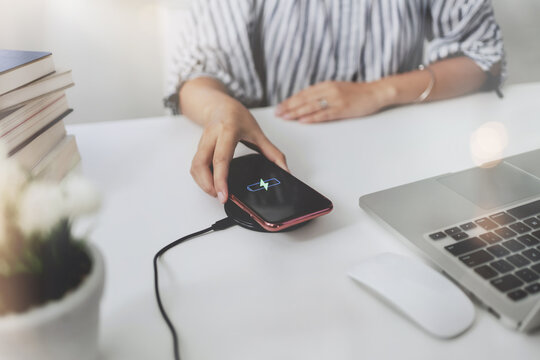 Woman charging a smartphone with wireless charger at home.