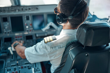 Male pilot flying passenger plane on sunny day - obrazy, fototapety, plakaty