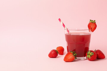 Glass with fresh strawberry juice on pink background