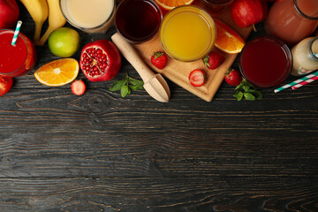 Glasses and jars with different juices on wooden background