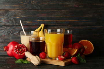 Glasses and jars with different juices on wooden background