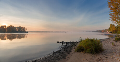 Plain river with sandy bank and trees autumn at sunrise