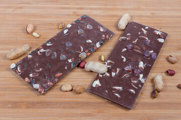 Bars of chocolate with nuts among the scattered various nuts