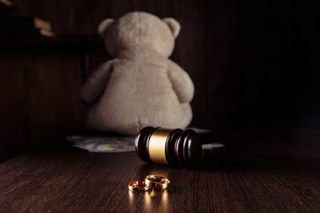 Wooden judge gavel with rings and teddy bear dollar banknotes. Divorce and alimony concept.