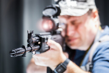 man looks into the scope of a machine gun. Focus on the muzzle brake-compensator. Selective focus. The person is not recognizable and is very blurry