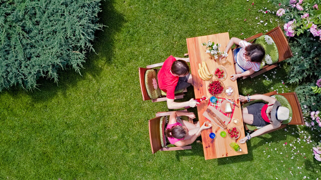 Family And Friends Eating Together Outdoors On Summer Garden Party. Aerial View Of Table With Food And Drinks From Above. Leisure, Holidays And Picnic Concept
